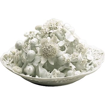 Teller mit durchbrochenem Rand, auf dem naturalistisch gestaltete Blumen und Früchte aus Porzellan arrangiert sind.