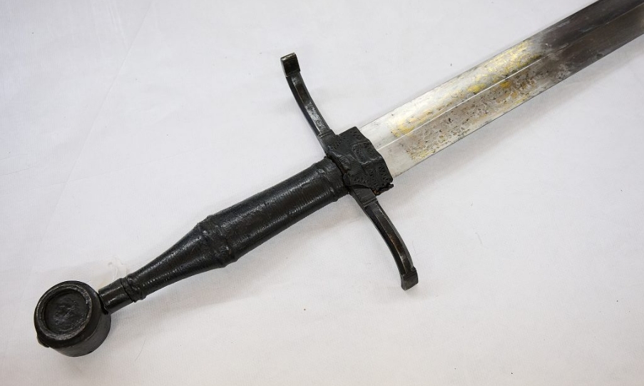 Mittelalterliches Schwert mit gerader Klinge, Parierstange und rundem Knauf, Detailansicht von Griff und Klingenansatz, Sammlung des Badischen Landesmuseums als Zeugnis historischer Waffenkultur.