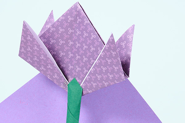 Gefaltete Origami-Blume aus lilafarbenem Papier vor hellem Hintergrund. Die stilisierte Papierblüte verbindet kreatives Gestalten mit floraler Kultur im Kontext des Badischen Landesmuseums.