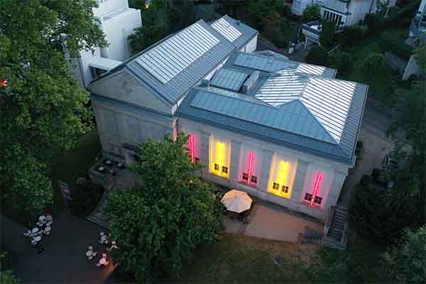 Staatliche Kunsthalle Baden-Baden, Außenansicht des klassizistischen Gebäudes mit farbig beleuchteten Fenstern im Abendlicht.