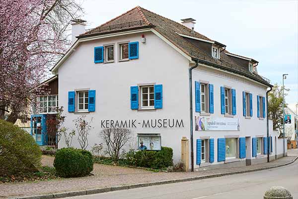 Außenansicht des Keramikmuseums Staufen im Breisgau, ein weißes Gebäude mit blauen Fensterläden und der Aufschrift „Keramik-Museum“. Das Haus steht an einer Straße und repräsentiert regionale Kultur und Sammlungskontexte des Badischen Landesmuseums.