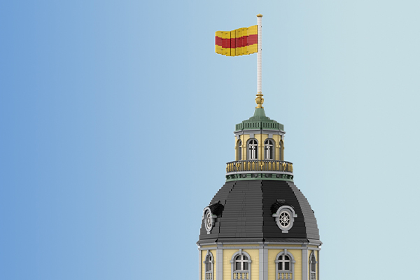 Detailaufnahme des Turms des Karlsruher Schlosses als Klemmbausteinmodell. Zu sehen ist die Kuppel mit Laterne, umlaufender Galerie und gehisster badischer Flagge auf der Spitze.
