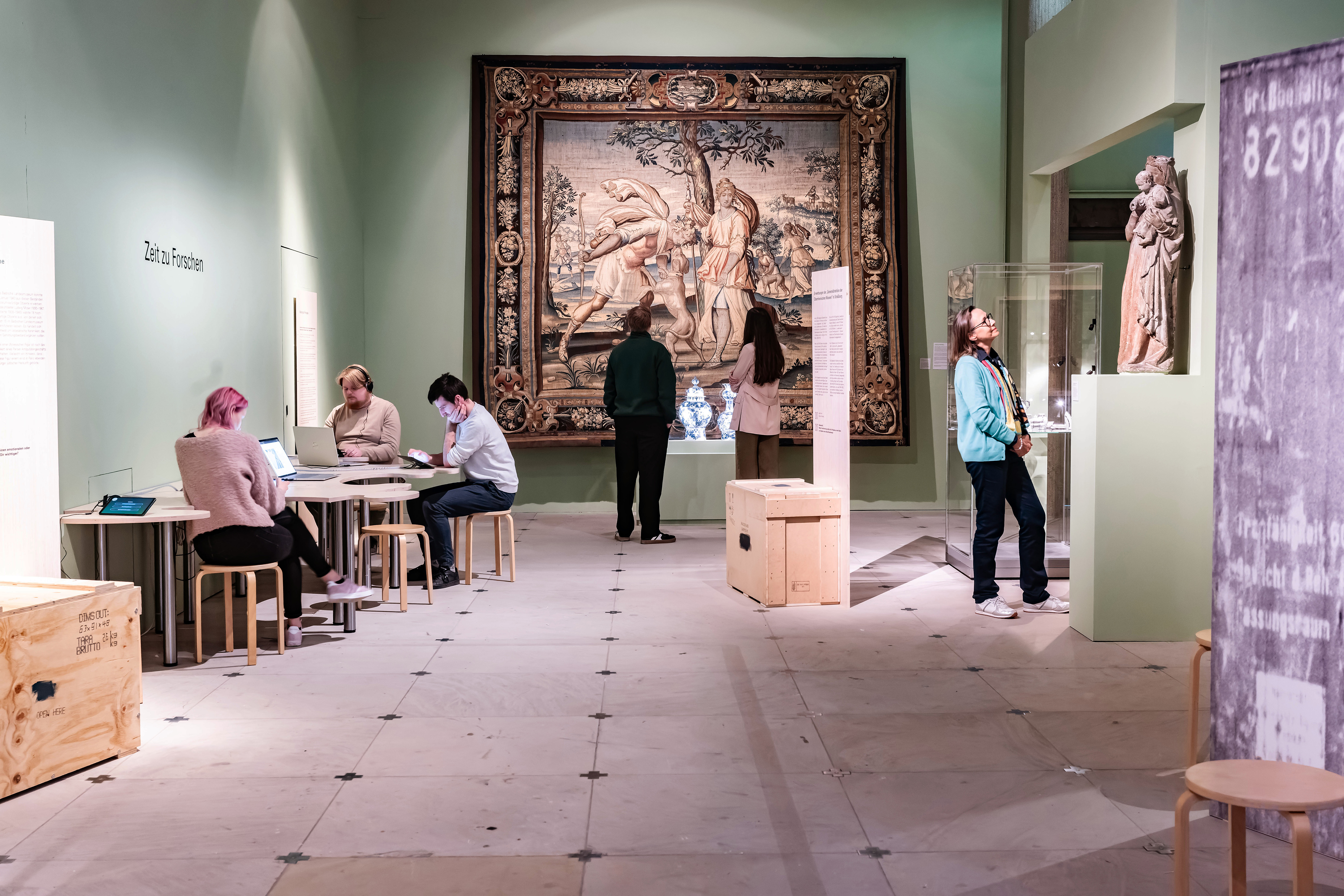 Besucher in einer Ausstellung, einige betrachten einen großen Wandbehang