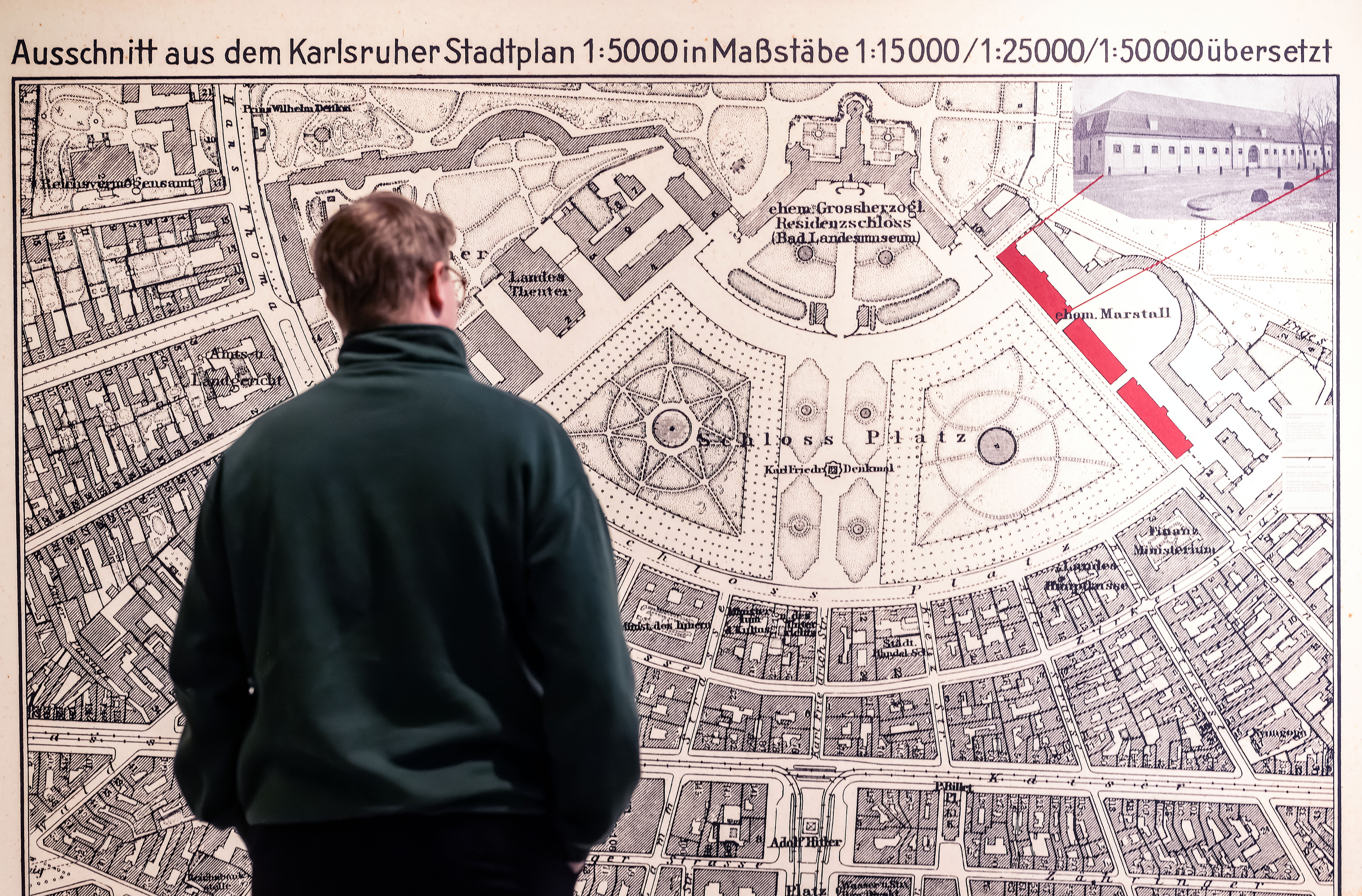 Besucher betrachtet einen historischen Stadtplan von Karlsruhe