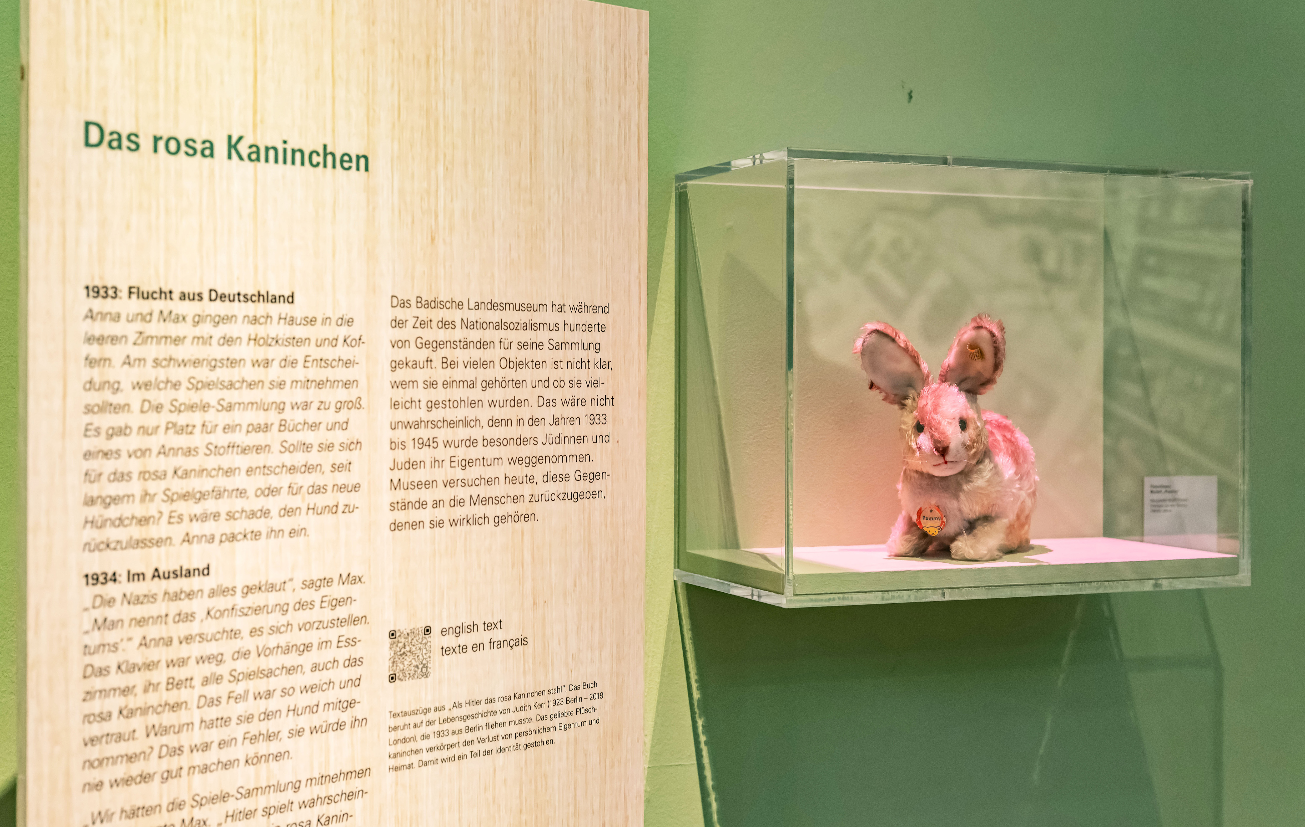 Auf einer Holztafel stehen Text-Auszüge aus dem Roman "Als Hitler das rosa Kaninchen stahl", daneben befindet sich eine Vitrine mit einem rosa Plüschhasen 