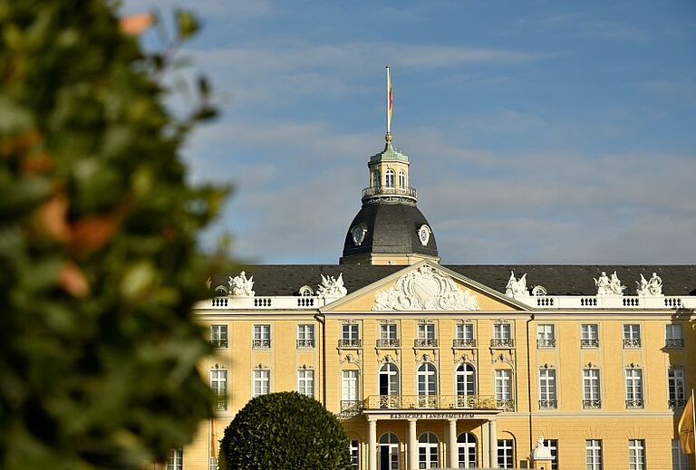 Das Karlsruher Schloss mit seiner gelben Barockfassade und dem markanten Schlossturm im Sonnenlicht. Das historische Gebäude ist Sitz des Badischen Landesmuseums und ein zentraler Ort für Kultur, Ausstellungen und Events in Karlsruhe.
