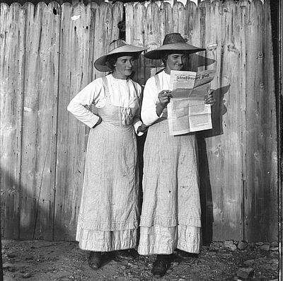 wei Elsässerinnen beim Lesen der „Straßburger Post", stehend an einem Zaun. Schwarzweißphotographie.