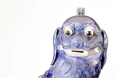 Blau glasierte Wächterlöwen-Figur mit großen Augen und geöffnetem Maul, detailreich gearbeitetes Fell und dekorative Form, Sammlung des Badischen Landesmuseums als Beispiel ostasiatischer Kultur und Schutzsymbolik.