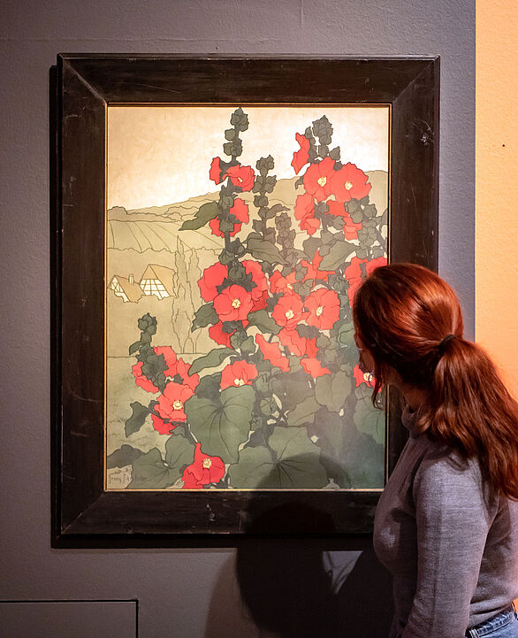 Eine Frau betrachtet ein Gemälde, das Blumen zeigt.