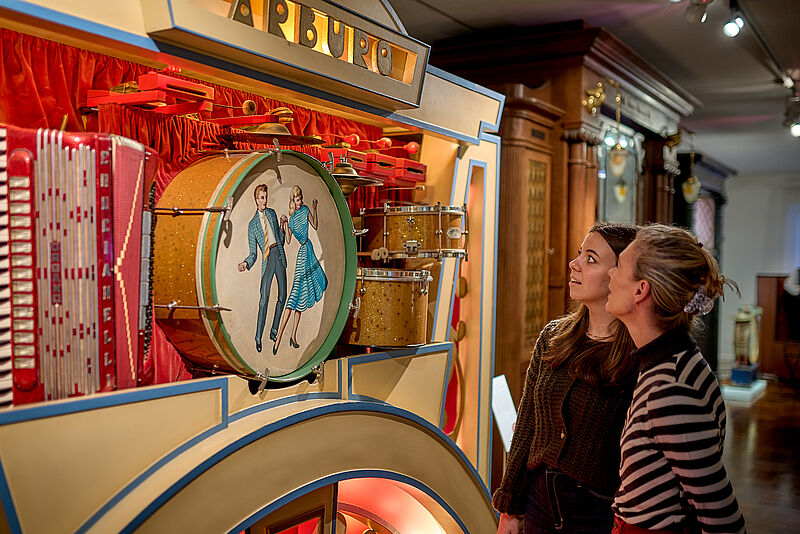 Zwei Personen betrachten einen Musikautomaten