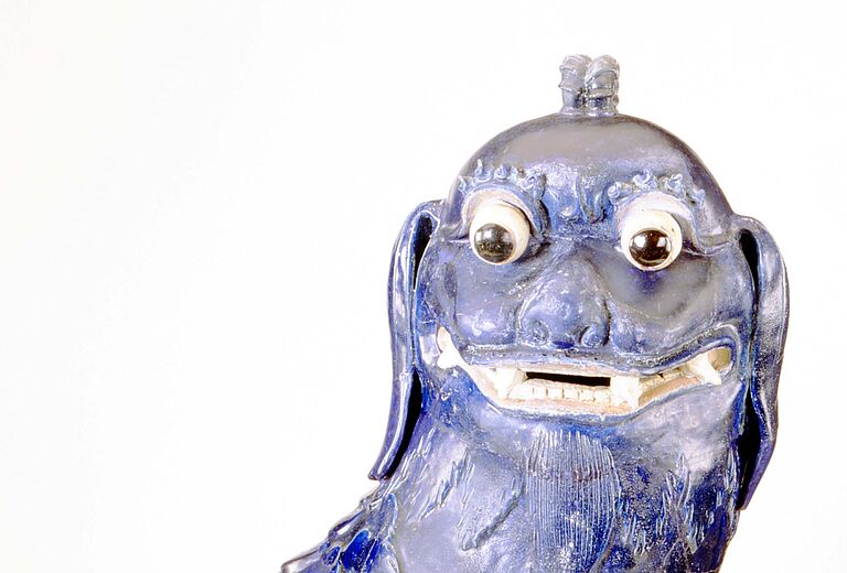 Blau glasierte Wächterlöwen-Figur mit großen Augen und geöffnetem Maul, detailreich gearbeitetes Fell und dekorative Form, Sammlung des Badischen Landesmuseums als Beispiel ostasiatischer Kultur und Schutzsymbolik.