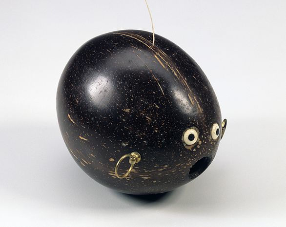 Die geschliffene und polierte Kokosnuss diente wohl als Pulverflasche. Exotische Früchte wie die Kokosnuss waren im 16. und 17. Jahrhundert kostbar und begehrt und wurden häufig aufwendig verarbeitet. Hier wurde die Nuss zu einem Gesicht gestaltet, die kreisförmige Öffnung (der Mund) wird von einem aus Elfenbein und Ebenholz gebildeten Augenpaar flankiert.