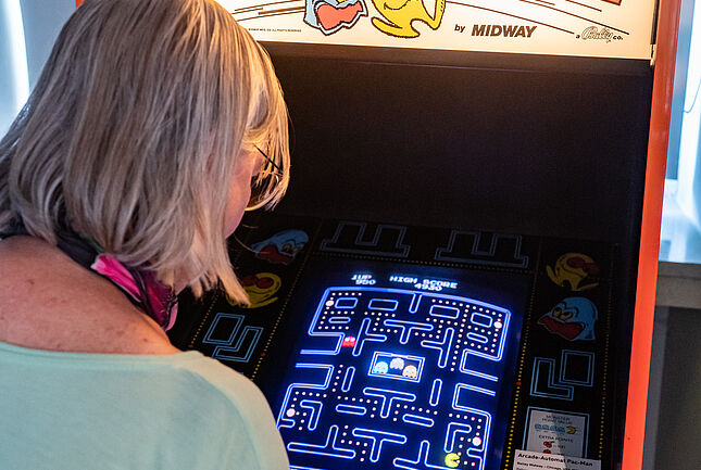 Eine Person spielt an einem Pac-Man-Automaten.