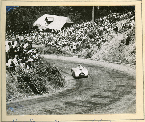 Photo of an automobile racer on the track with spectators