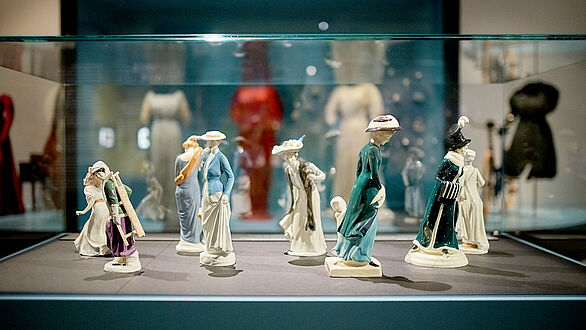 Blick in eine Vitrine mit Porzellanfiguren von Frauen.