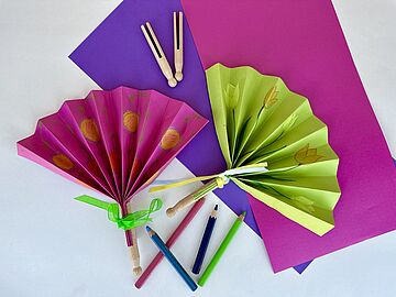 Aus Papier gebastelte Fächer in verschiedenen Farben