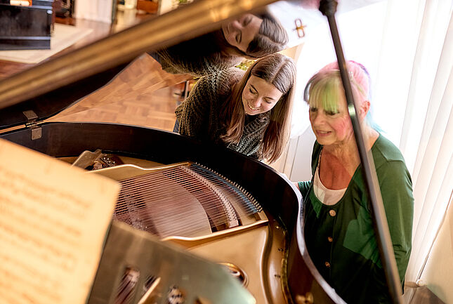 Besucherin und Kind blicken von oben auf das Innenleben eines Musikautomaten