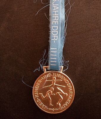 Bronzene Sportmedaille an einem blauen Band.
