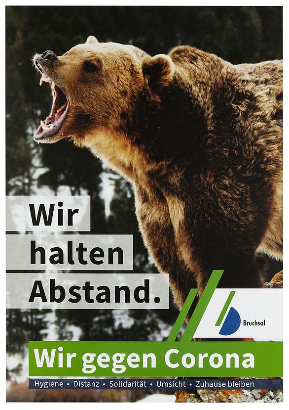 Plakatkampagne der Stadt Bruchsal von März bis Juni 2020, hier mit einem gefährlich wirkenden Bären, der das Maul aufreißt mit dem Text: "Wir halten Abstand. Wir gegen Corona"