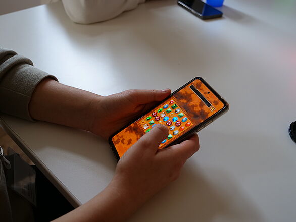 Nahaufnahme von Händen, die auf einem Smartphone "King Karl" spielen