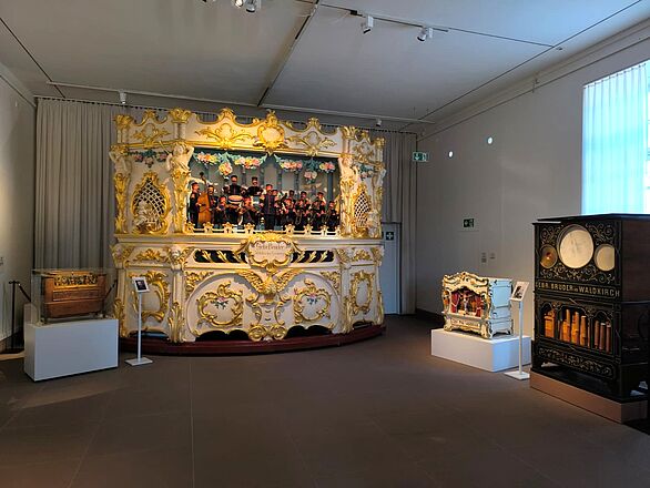 Blick in die Ausstellung des Deutschen Musikautomaten-Museums mit mehreren historischen Musikautomaten, darunter eine große, reich verzierte Jahrmarktsorgel und eine Orgel der Gebrüder Bruder aus Waldkirch. Das Badische Landesmuseum präsentiert hier Kultur und Technikgeschichte der mechanischen Musik.