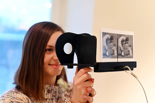 Eine junge Frau blickt durch eine Loch-Kamera