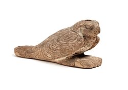 Kleine Tierfigur aus hellem Holz in Form einer Robbe mit stilisiertem Kopf und eingeritzter Fellstruktur. Das Objekt aus der Sammlung des Badischen Landesmuseums veranschaulicht die Darstellung von Tieren in der Kultur und im kunsthandwerklichen Schaffen.