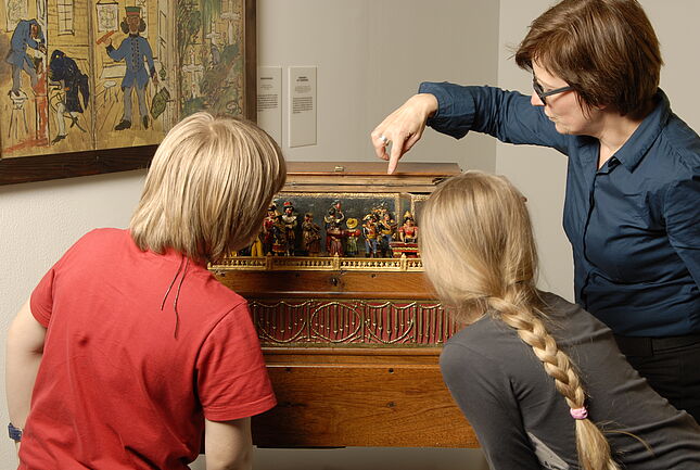 Vermittlerin führt zwei Kindern Orgel vor