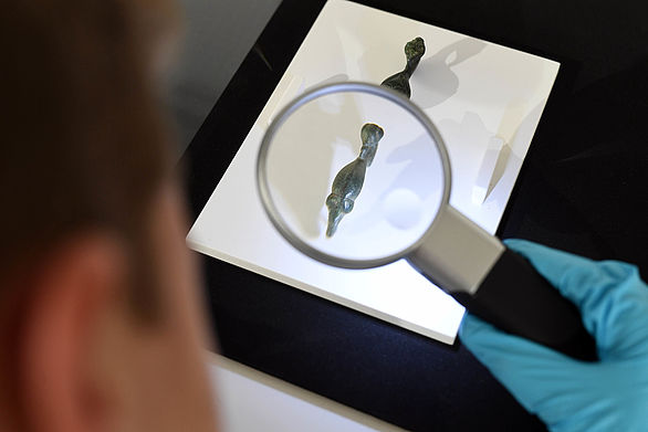 A visitor examines an object with a magnifying glass