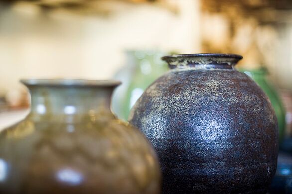 Zwei bauchige Keramikvasen von Egon Bregger im Keramikmuseum Staufen. Die Gefäße zeichnen sich durch ihre schlichten Formen und zurückhaltende Gestaltung aus. Eine dunkelblau schimmernde, strukturierte Glasur kontrastiert mit der helleren, olivgrünen Keramik im Vordergrund. Die Ausstellung des Badischen Landesmuseums vermittelt regionale Keramikkultur und handwerkliche Gestaltung.